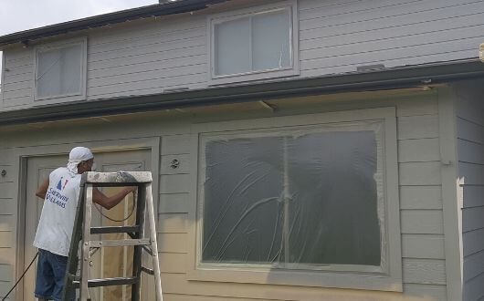 Painting the siding of a house in Tomball Texas